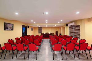 a conference room with red chairs and a podium at Hotel Indraprastha Karunagapally in Panmana