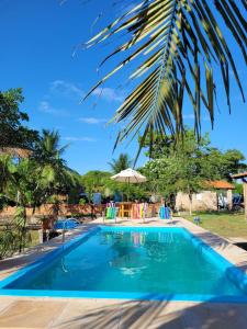 a swimming pool with chairs and an umbrella at Casa em condominio com piscina na beira do rio Alegre in Santo Amaro +10 photos