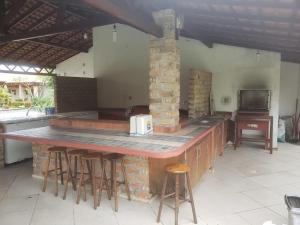 an outdoor kitchen with a counter and bar stools at Casa em condominio com piscina na beira do rio Alegre in Santo Amaro