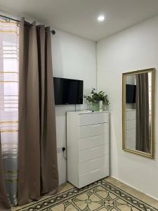 a room with a television and a dresser with a mirror at Coral Reef Charming studio by the three old cities in Cospicua +6 photos