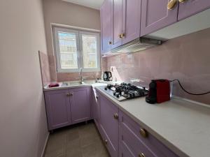 a purple kitchen with a stove and a sink at Estia Alternative Apartment in Drama