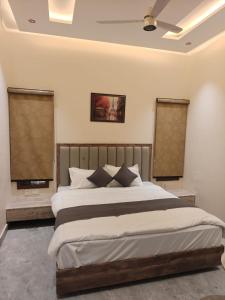 a bedroom with a large bed and two windows at Hotel Natraj Sirsa in Sirsa