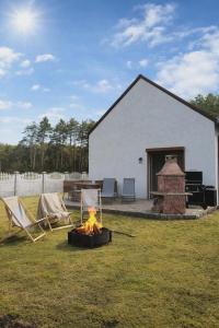 a fire pit in a yard with chairs and a building at Leśny Domek in Piłka
