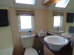 a bathroom with a toilet and a sink and two windows at Washington Lodge in Heacham