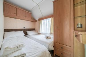 a small bedroom with two beds and a window at Washington Lodge in Heacham