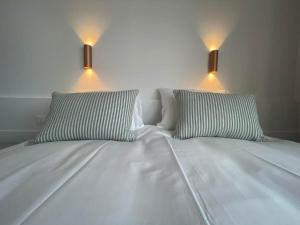 a white bed with two pillows and two lights on it at Strandhotel De Haan in De Haan