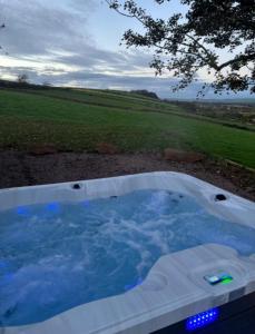 a jacuzzi tub with a view of a field at Caerlaverock Glamping - Sycamore in Dumfries