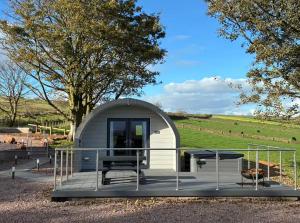 a small shed with a table and benches on a deck at Caerlaverock Glamping - Sycamore in Dumfries