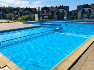 a large swimming pool with blue water at Apartament szafirowy z basenem koło Łeby in Żarnowska