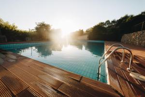 a large swimming pool with the sun in the background at Vall d'Àger Resort & Camping in Àger