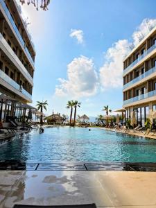 a large swimming pool in a resort with palm trees at Elite Sunset Residence in Vlorë