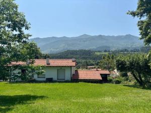 a house in a field with mountains in the background at Chalet con jardín junto a playas in Colunga