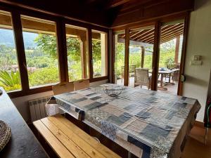 a dining room with a large table and windows at Chalet con jardín junto a playas in Colunga +30 photos