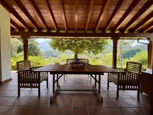 a wooden table and chairs on a patio with a tree at Chalet con jardín junto a playas in Colunga