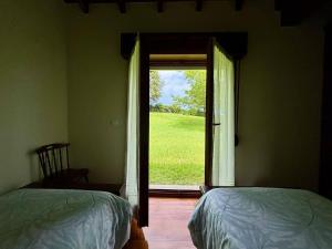 a bedroom with two beds and a door to a window at Chalet con jardín junto a playas in Colunga