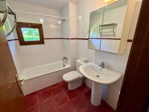 a white bathroom with a sink and a toilet at Chalet con jardín junto a playas in Colunga