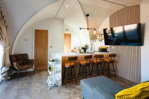 a kitchen with a bar with stools and a tv at Pheasant Lodge in Little Bytham
