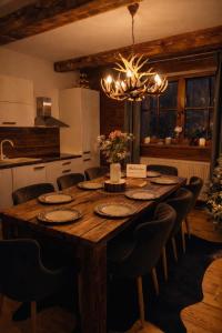 a kitchen with a large wooden table with chairs and a chandelier at Rioba Chalet in Nová Bystrica +21 photos