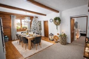 a dining room with a table and chairs and a christmas tree at Rioba Chalet in Nová Bystrica