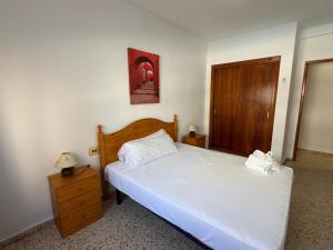 a bedroom with a white bed and a wooden cabinet at Wimpy Solo Familias Serviplaya in Playa de Xeraco +8 photos