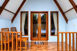 a wooden door in a room with a table and chairs at Harmony Beachfront Bungalow in Gili Meno