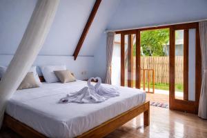 a bedroom with a bed with white sheets and a window at Harmony Beachfront Bungalow in Gili Meno