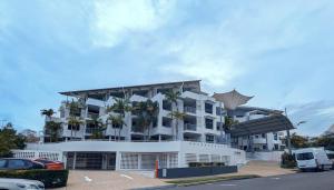 a large white building with palm trees in a parking lot at Beach and Breeze in Mooloolaba