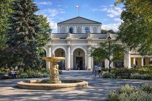 a building with a fountain in front of it at Szmaragdowa Przystań - apartament z parkingiem blisko Parku Zdrojowego i Tężni in Busko-Zdrój