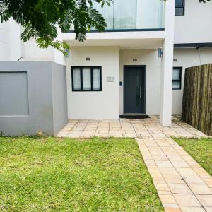 a white house with a black door at 219 Contours Luxury Apartment in Victoria Falls