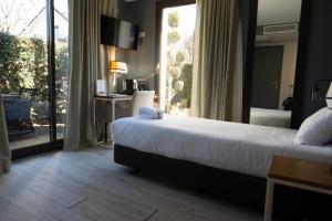 a bedroom with a bed and a large window at Hôtel Les Muses in Annecy