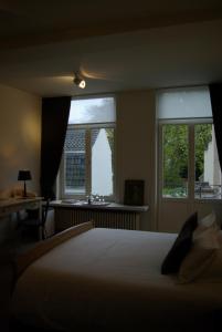 Un dormitorio con una cama y dos ventanas. en B&B Huyze Weyne, en Brujas
