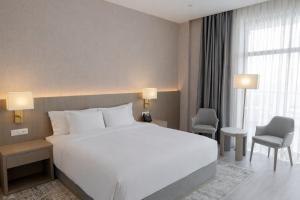 a hotel room with a large white bed and chairs at Yevlakh City Hotel in Yevlax +62 photos