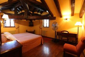 a bedroom with a bed and a desk and a fan at Posada Palacio de Beola by Clabao in Almándoz
