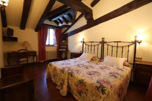 a bedroom with a bed with a floral bedspread at Posada Palacio de Beola by Clabao in Almándoz