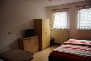 a bedroom with a bed and a cabinet and two windows at Ferienhaus Grasse in Görlitz