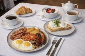 ein Tisch mit Tellern mit Frühstücksspeisen und Tassen Kaffee in der Unterkunft Birmingham Great Barr Hotel in Birmingham