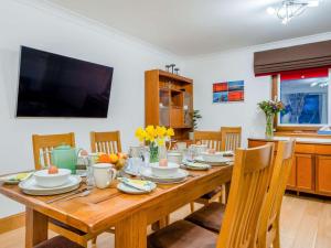 a dining room table with chairs and a television at 3 Bed in Bathgate oc-90491 in Fauldhouse