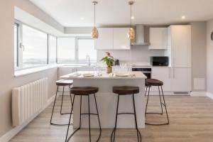 a kitchen with white cabinets and a island with bar stools at Metro Hotel Dublin Airport in Santry