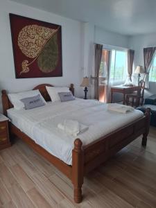 a bedroom with a large bed with white sheets at Cozy Country House with Pool in Ban Nong Nam Khem