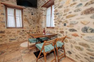a table and chairs in a room with a stone wall at Mystras Panorama House in Mystras