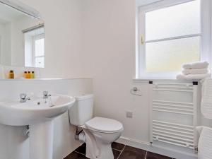 a white bathroom with a toilet and a sink at 1 Bed in Ardross oc-95533 in Alness