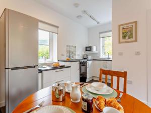 a kitchen with a wooden table and a kitchen with a refrigerator at 1 Bed in Ardross oc-95533 in Alness +12 photos