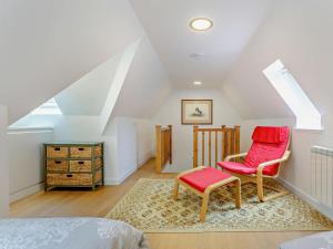 a attic bedroom with a red chair and a stool at 1 Bed in Ardross oc-95533 in Alness