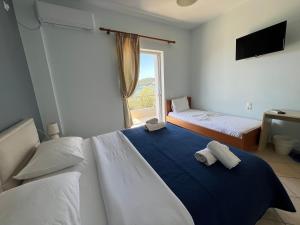 a bedroom with two beds and a window at Hotel Prinos in Himare