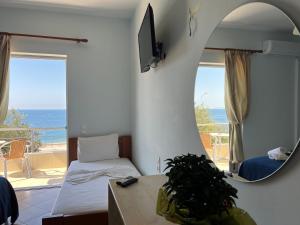 a room with a bed and a mirror and a balcony at Hotel Prinos in Himare