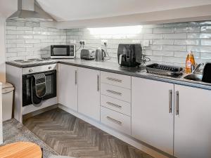 a kitchen with white cabinets and a microwave at Lily - Uk49362 in Bridlington