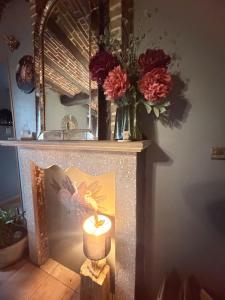 a candle sitting on top of a fireplace with flowers at Suite Home in Crespin +14 photos