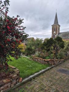 a church with a steeple and a yard with a yard sidx sidx at Suite Home in Crespin