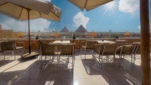 a balcony with tables and chairs and a view of the pyramids at panorama pyramids view inn in Cairo