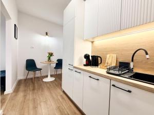 eine Küche mit weißen Schränken und einem Tisch mit Stühlen in der Unterkunft Virta 8 in Ostróda